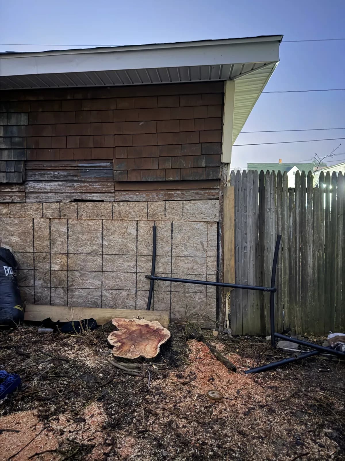 Small tree stump left after removal near a fence and building in a tight Buffalo NY yard